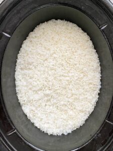 overhead shot of cooked white rice in a black slow cooker