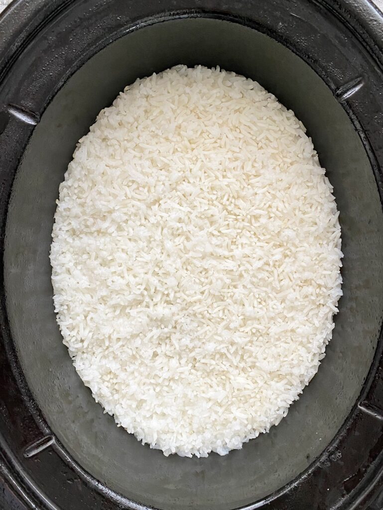 overhead shot of cooked white rice in a black slow cooker
