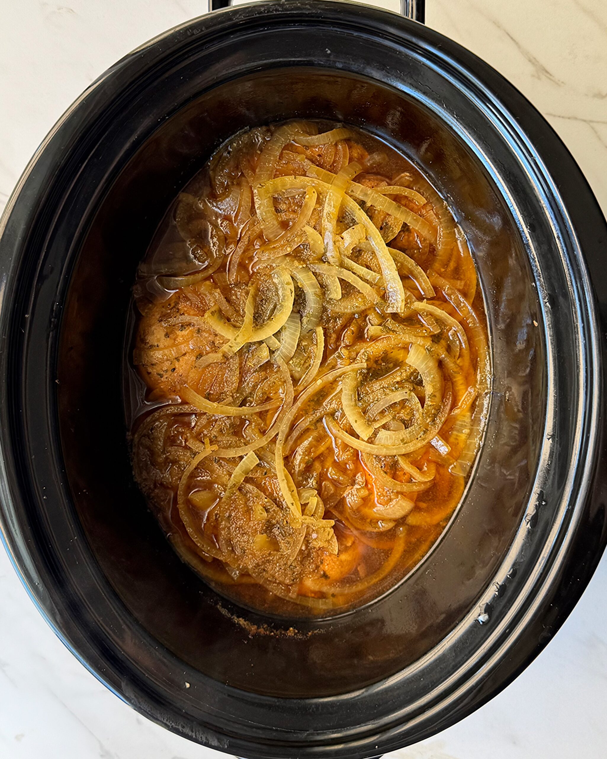 overhead shot of cooked French Onion Chicken in a black slow cooker