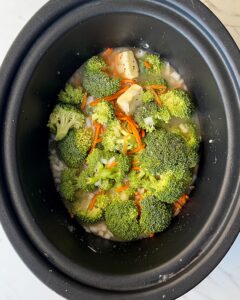 overhead shot of uncooked Broccoli Cheddar Soup in a black slow cooker