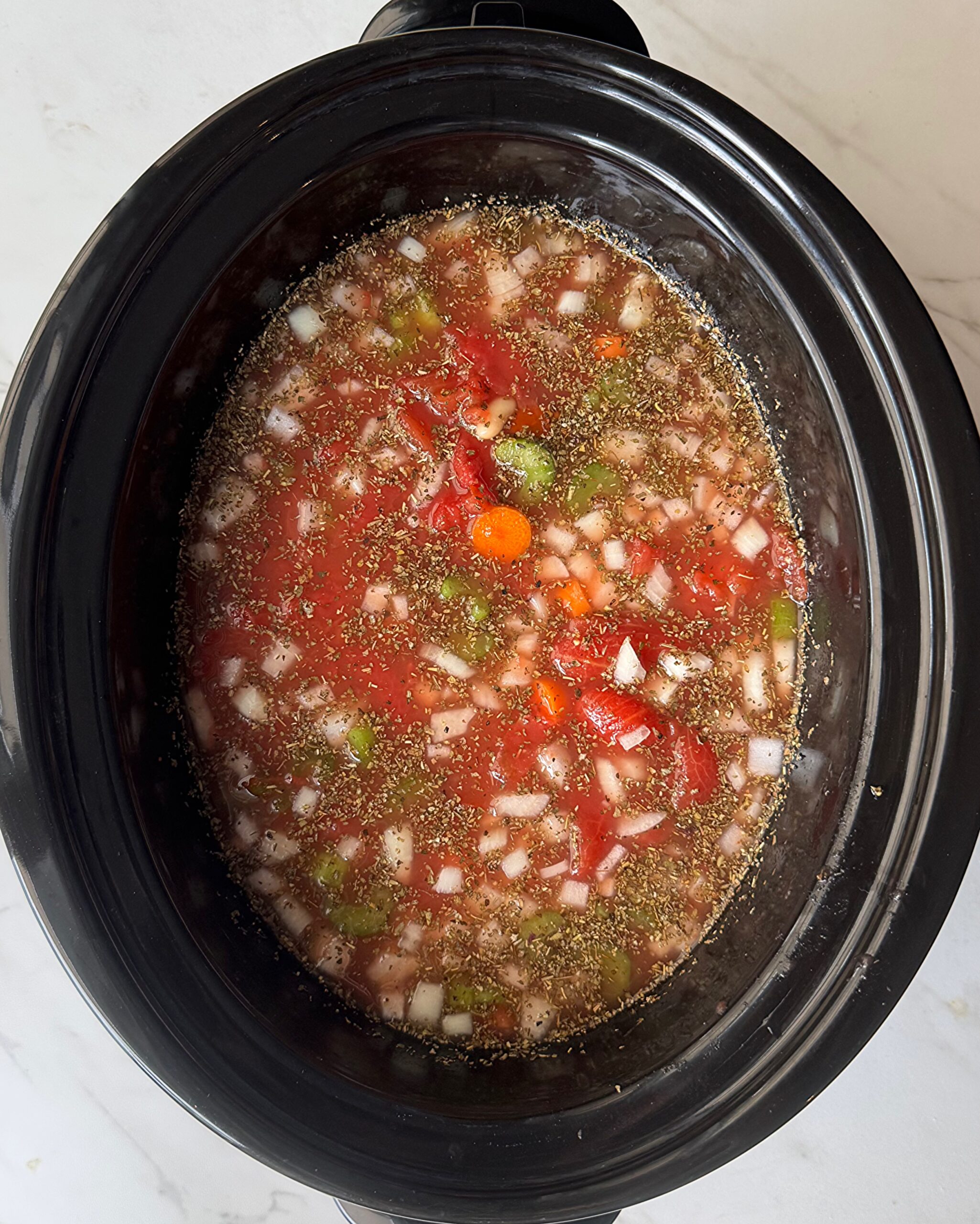 overhead shot of uncooked ribollita in a black slow cooker