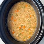 overhead shot of cooked Chicken and Rice Soup in a black slow cooker.