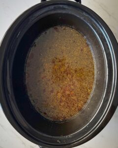 overhead shot of cooked creamy Ground Beef Pasta in a black slow cooker without the pasta and cream added