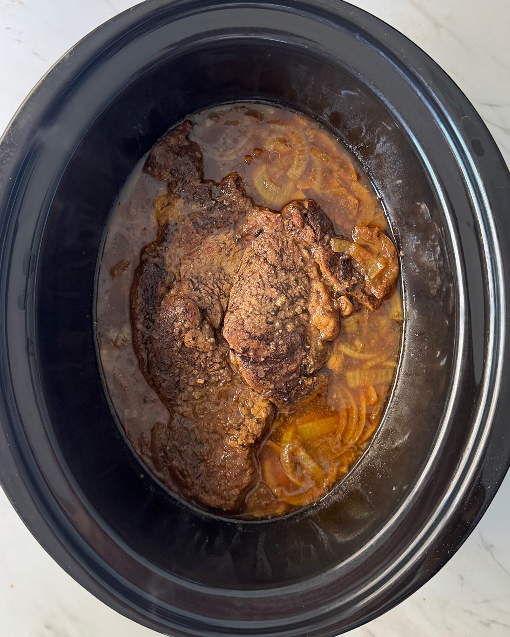 overhead shot of cooked French onion Pot Roast in a black slow cooker