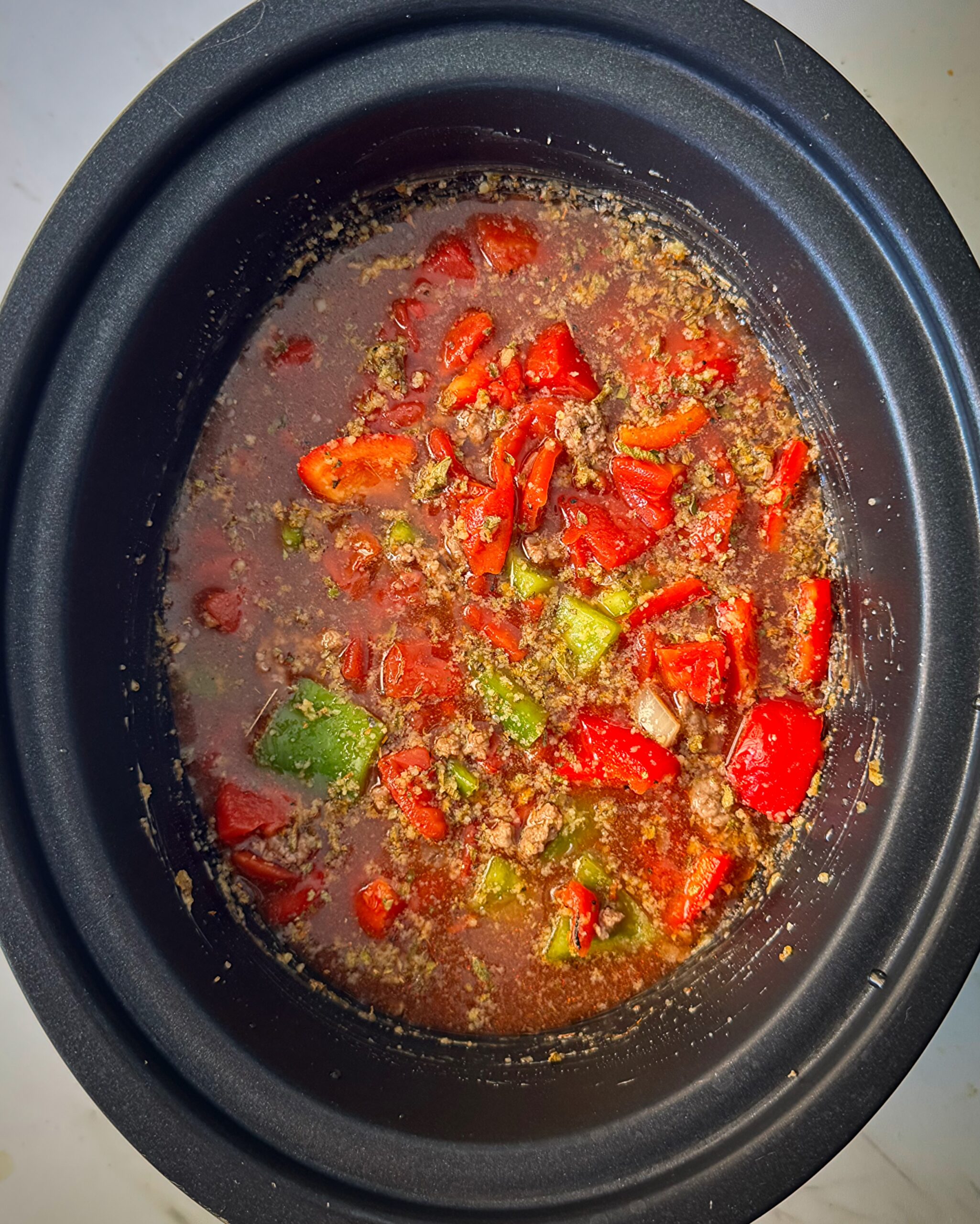 overhead shot of uncooked Stuffed Pepper Soup in a black slow cooker