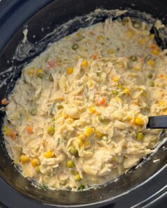 overhead shot of cooked chicken and noodles in a black slow cooker
