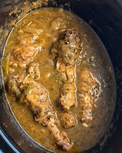 overhead shot of cooked Smothered Turkey Wings in a black slow cooker