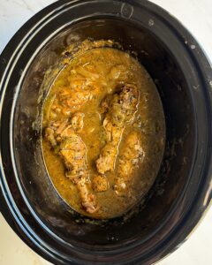 overhead shot of cooked Smothered Turkey Wings in a black slow cooker