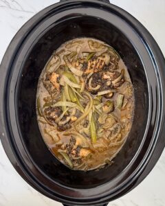 overhead shot of cooked Smothered Turkey Wings in a black slow cooker