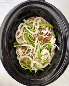 overhead shot of uncooked Smothered Turkey Wings in a black slow cooker