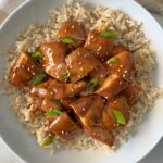 overhead shot of teriyaki chicken served over white rice garnished with green onion and sesame seeds