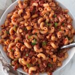 overhead shot of Slow Cooker American Goulash in a white bowl with a silver spoon