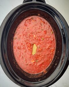overhead shot of uncooked ingredients for American Goulash in a black slow cooker