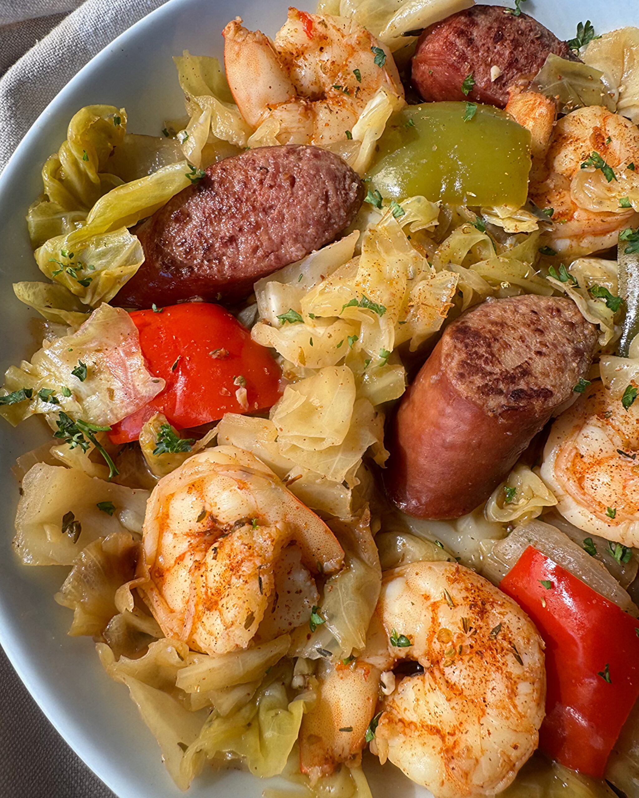 close up show of Crockpot Cajun Cabbage Sausage Shrimp on a white plate