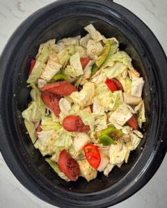 overhead shot of uncooked Cajun Cabbage Sausage Shrimp in a black slow cooker