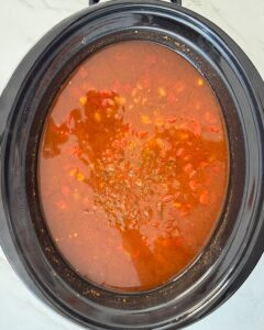 overhead shot of cooked chicken enchilada soup in a black slow cooker