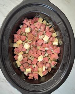 overhead shot of cooked corned beef and hash in a black slow cooker