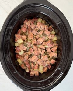overhead shot of cooked corned beef and hash in a black slow cooker