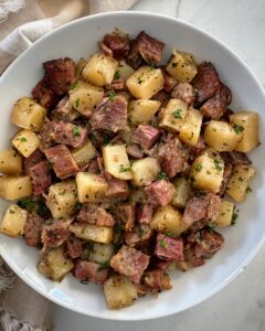 overhead shot of cooked corned beef and hash in a white plate
