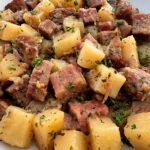 close up shot of cooked corned beef and hash in a white plate