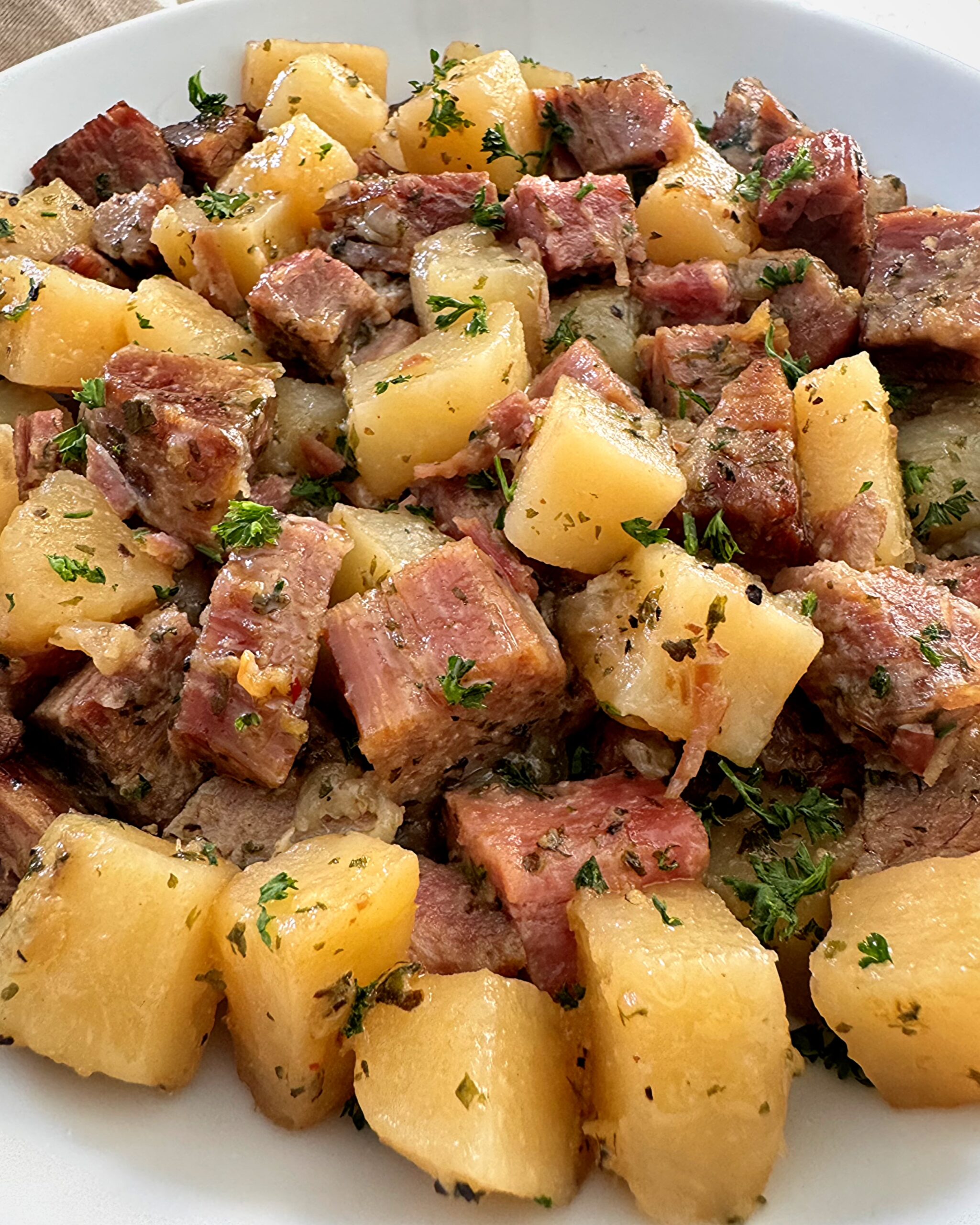 close up shot of cooked corned beef and hash in a white plate