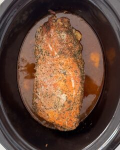 overhead shot of cooked slow cooker pork loin in a black slow cooker