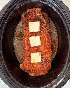 overhead shot of uncooked slow cooker pork loin in a black slow cooker