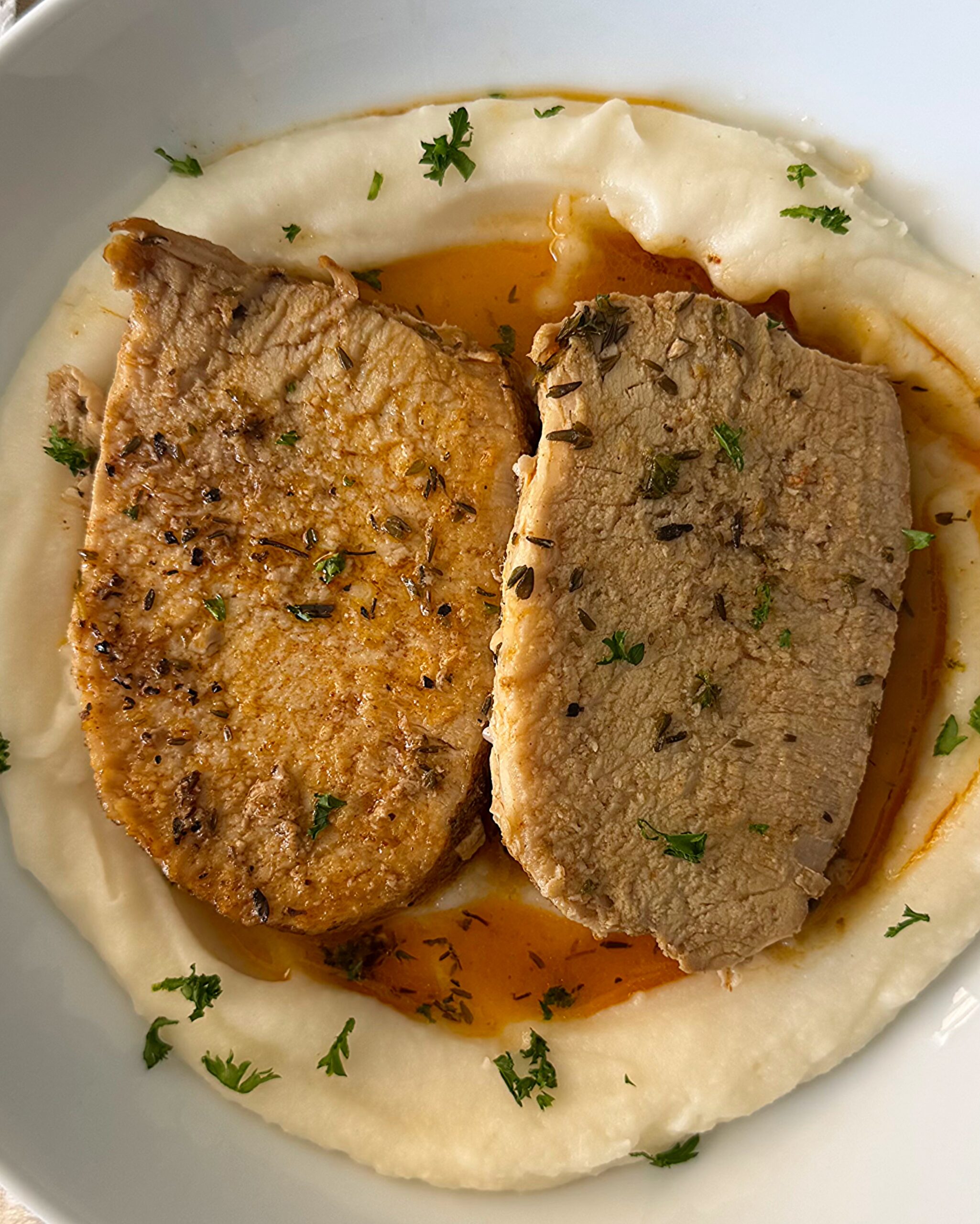 overhead shot of slow cooker pork loin served over mashed potatoes on a white plate
