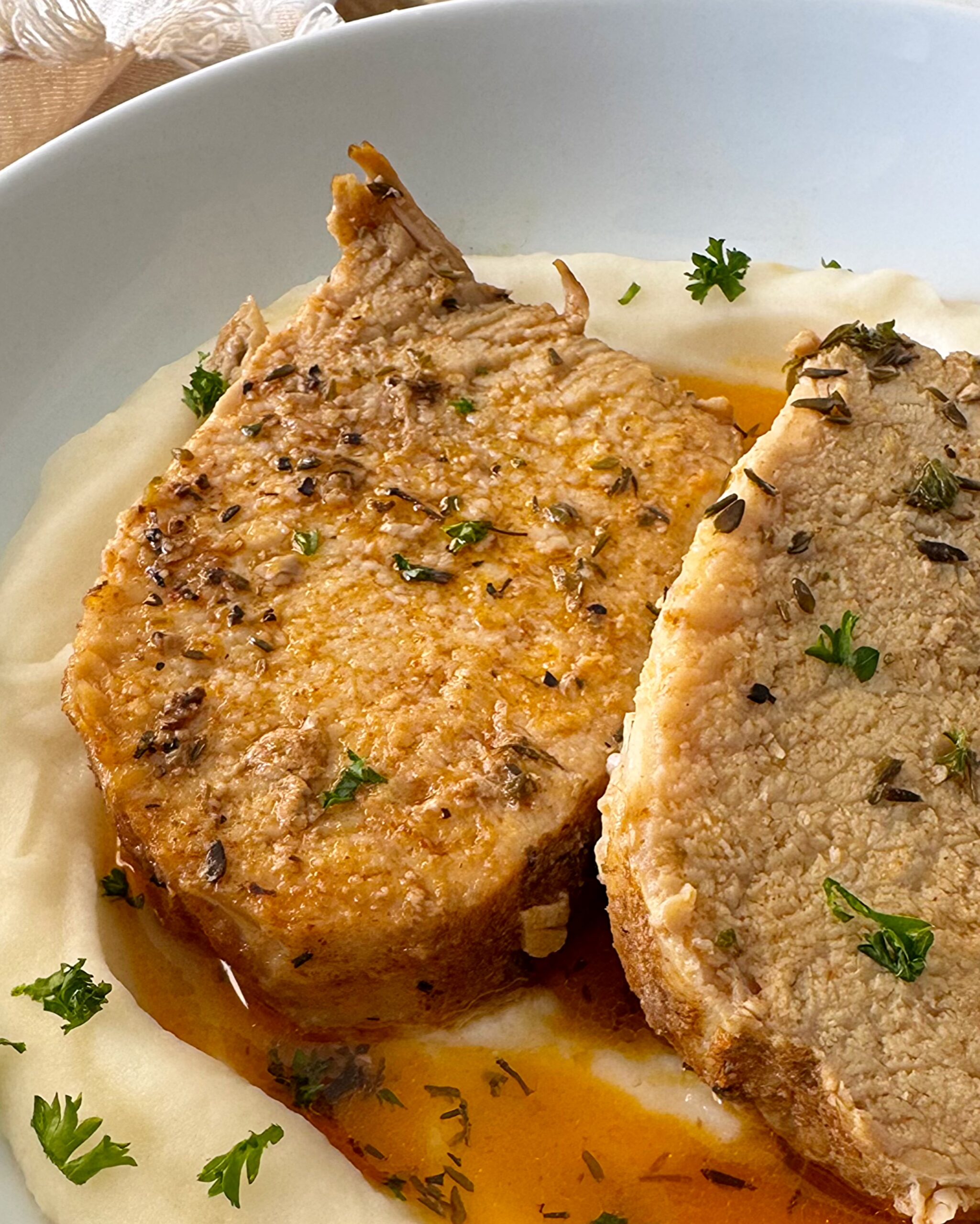 close up shot of slow cooker pork loin served over mashed potatoes on a white plate