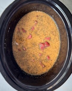overhead shot of uncooked beef tips & gravy in a black slow cooker