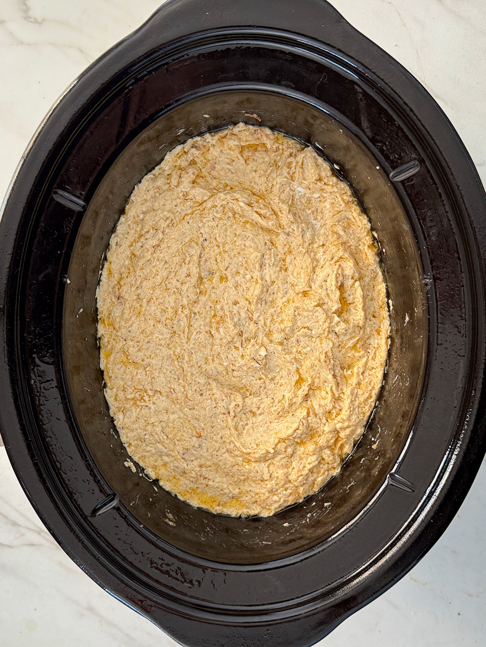 overhead shot of cooked crockpot crab in a black slow cooker