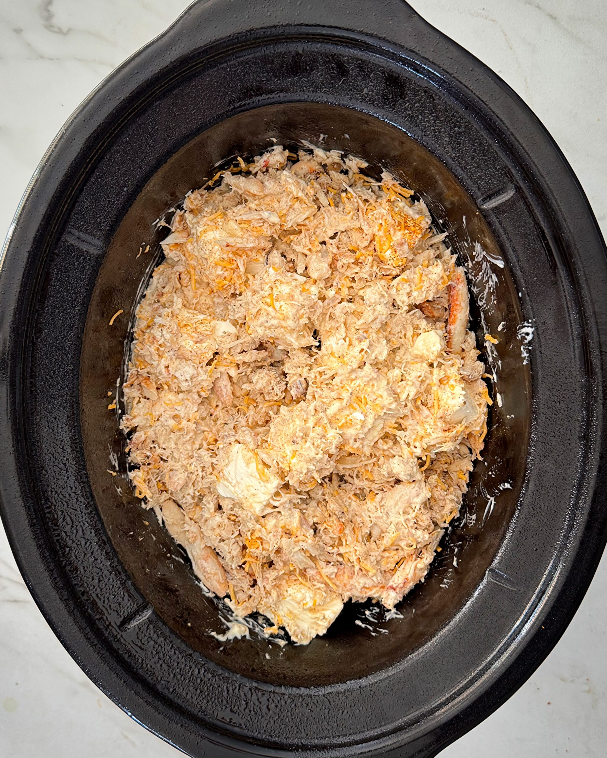 overhead shot of uncooked crockpot crab in a black slow cooker