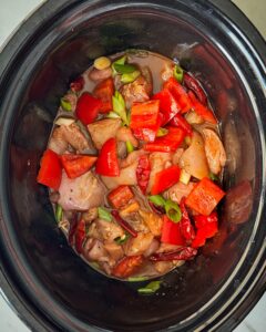 overhead shot of uncooked Kung Pao Chicken (Panda Express Copycat) in a black slow cooker