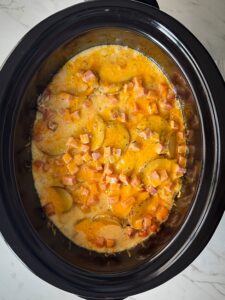 overhead shot of cooked Scalloped Potatoes and Ham in a black slow cooker