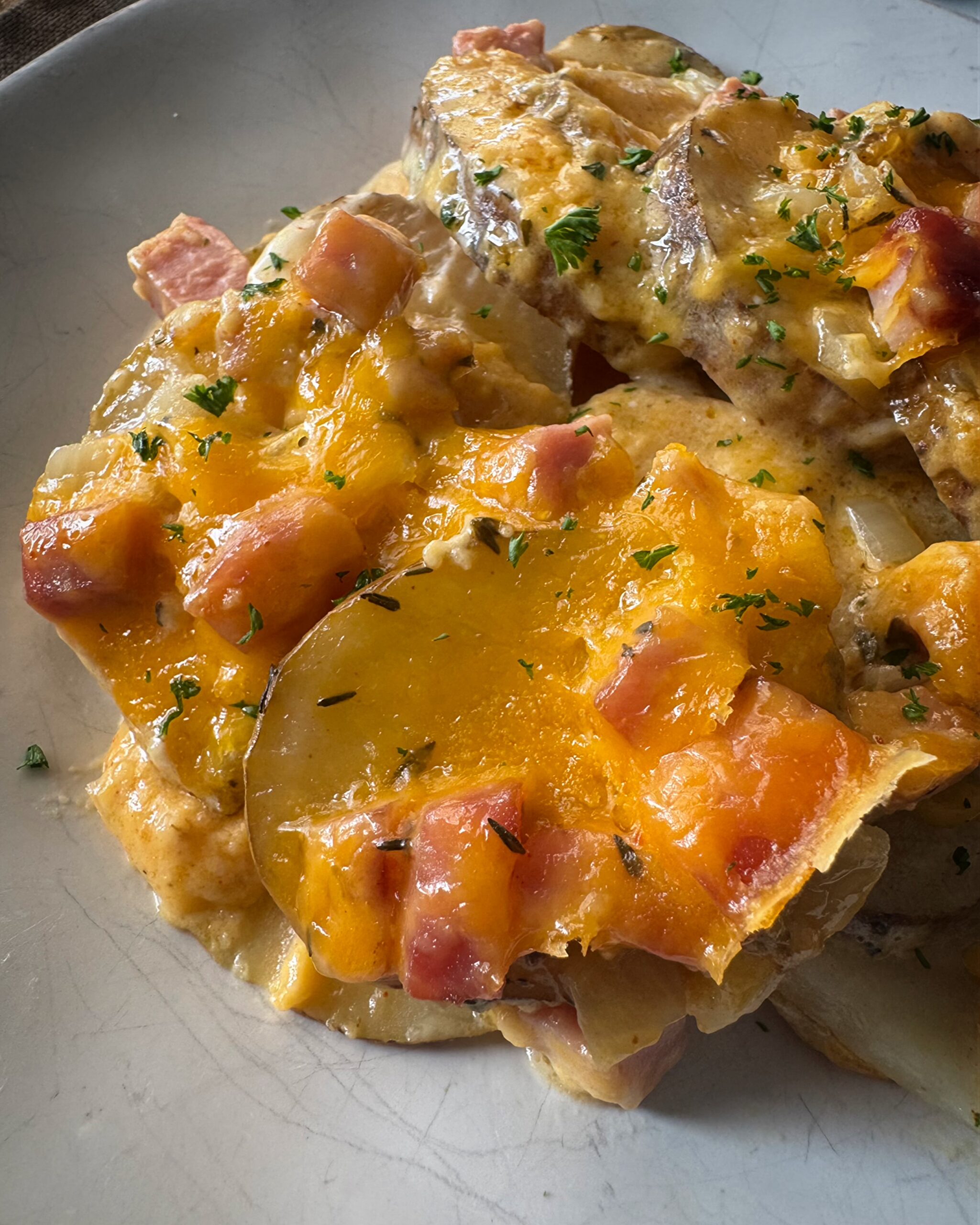 close up shot of cooked Crockpot Scalloped Potatoes and Ham on a white plate