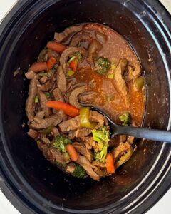 overhead shot of cooked Beef Stir-Fry in a black slow cooker