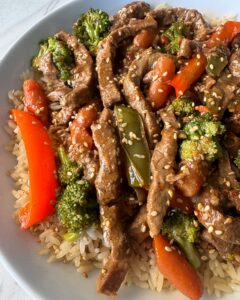 close up shot of slow cooker beef stir-fry served over rice on a white plate