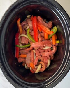 overhead shot of uncooked Beef Stir-Fry in a black slow cooker