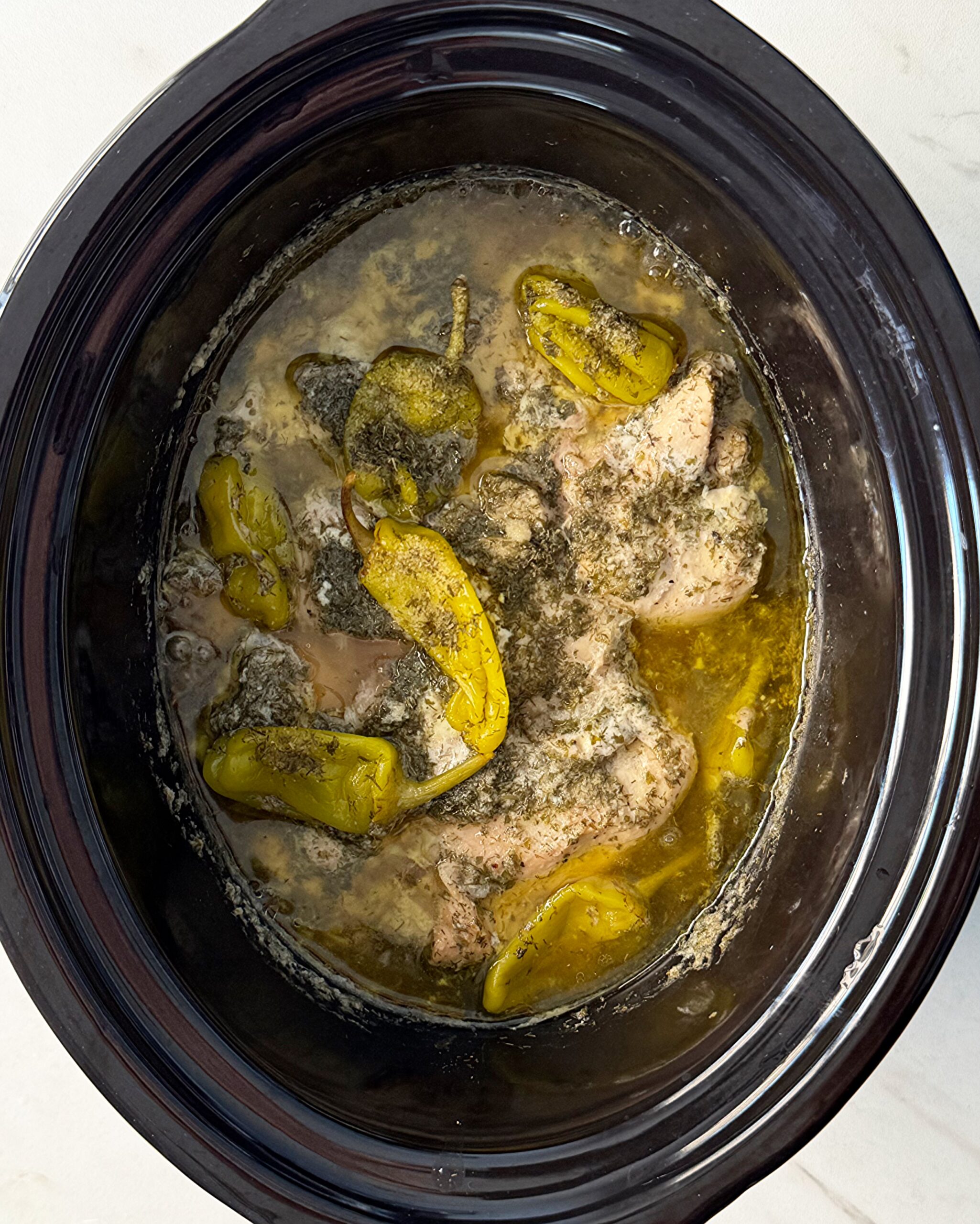 overhead shot of cooked Mississippi Chicken in a black slow cooker