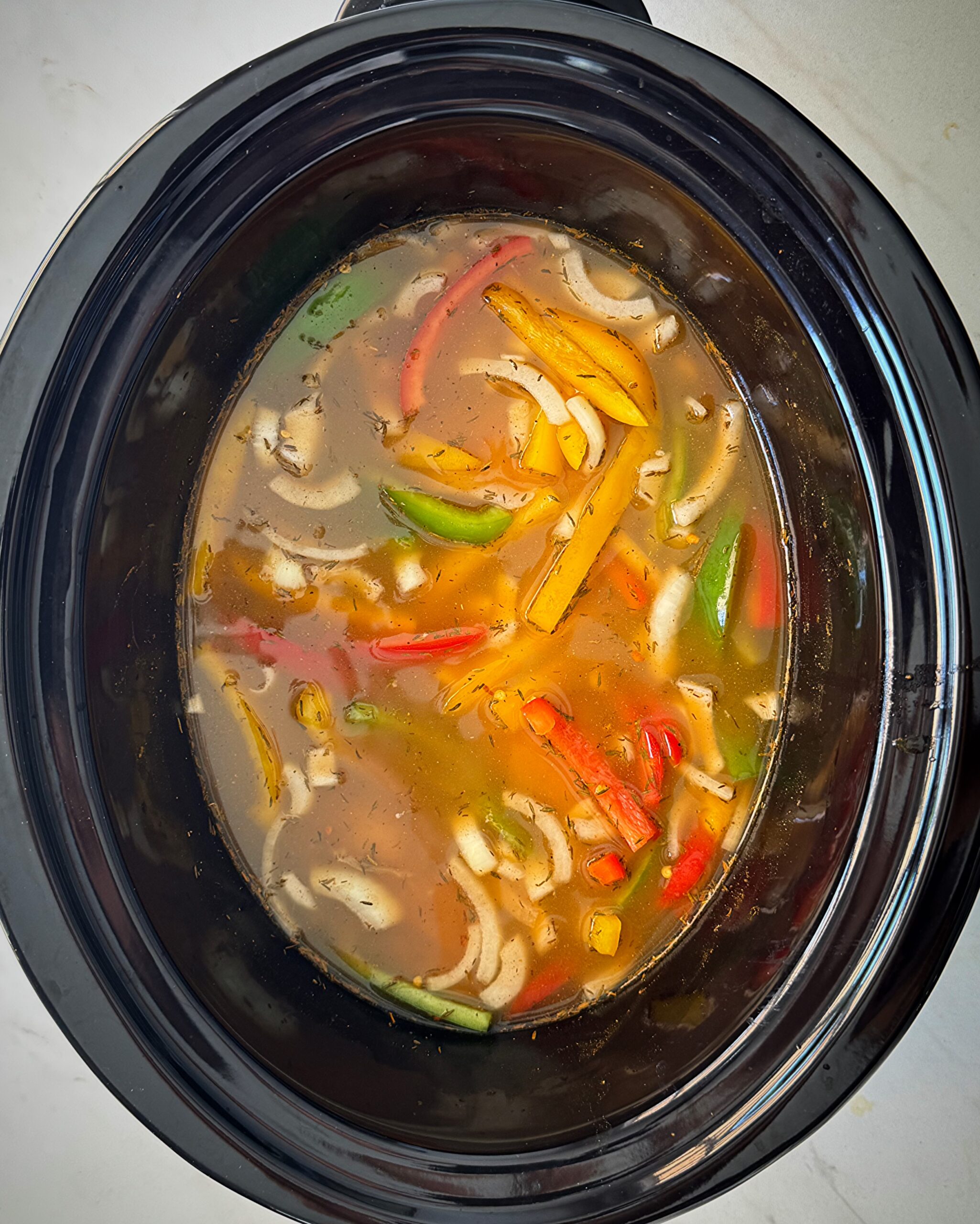 overhead shot of uncooked Rasta pasta in a black slow cooker