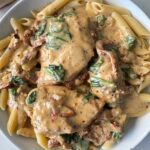 overhead shot of Tuscan chicken on a white plate served over penne pasta