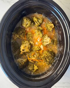overhead shot of cooked Chicken Broccoli Cheese Soup in a black slow cooker
