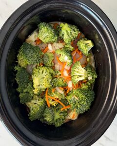 overhead shot of uncooked Chicken Broccoli Cheese Soup in a black slow cooker