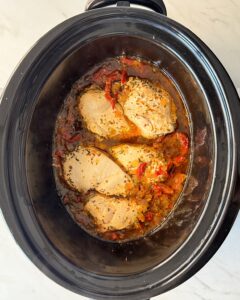 overhead shot of cooked marry me chicken in a black slow cooker