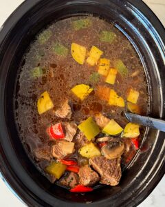 overhead shot of cooked beef kebab soup in a black slow cooker
