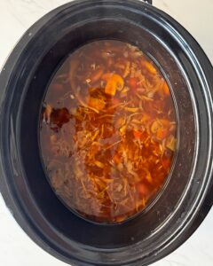 overhead shot of cooked potsticker soup in a black slow cooker
