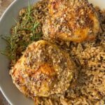 close up shot of Slow Cooker Rosemary Dijon Chicken served over a bed of rice garnished with fresh rosemary on a white plate