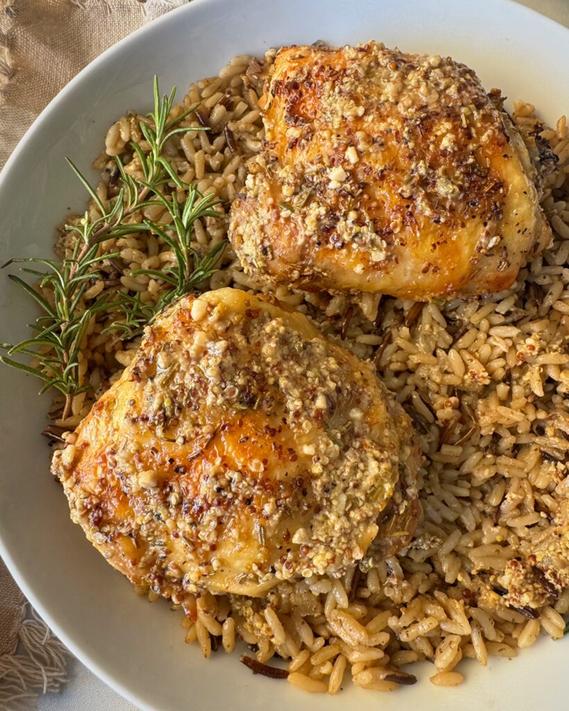 close up shot of Slow Cooker Rosemary Dijon Chicken served over a bed of rice garnished with fresh rosemary on a white plate