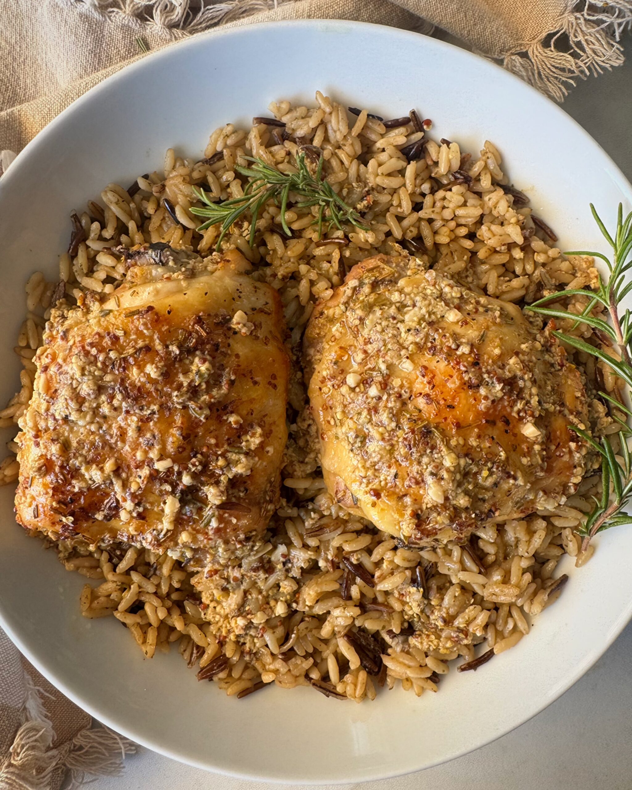 overhead shot of Slow Cooker Rosemary Dijon Chicken served over a bed of rice garnished with fresh rosemary on a white plate