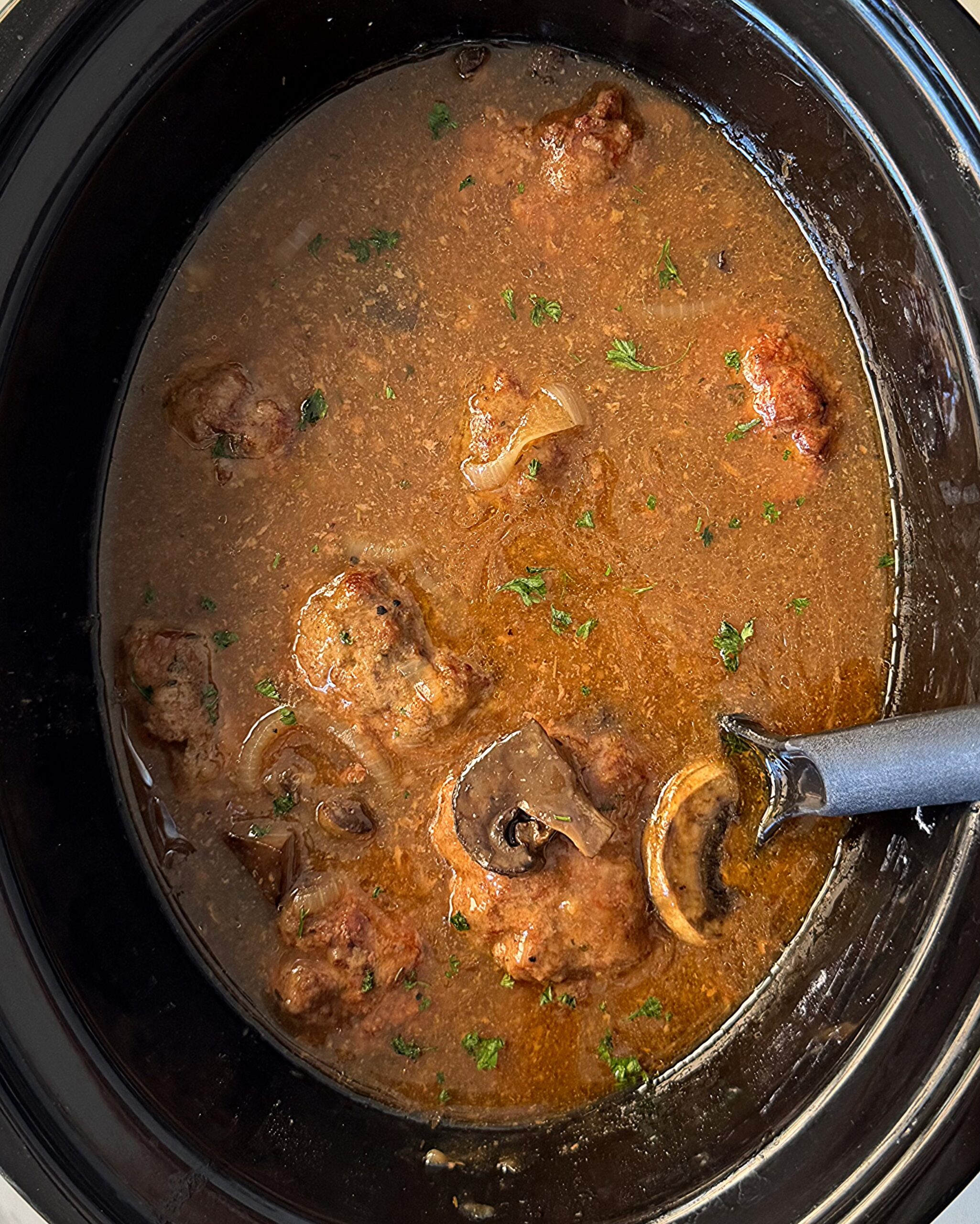 overhead shot of cooked Salisbury Steak in a black Slow Cooker